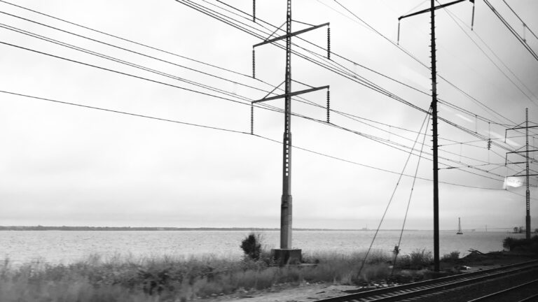 black and white photo of power lines along railroad tracks